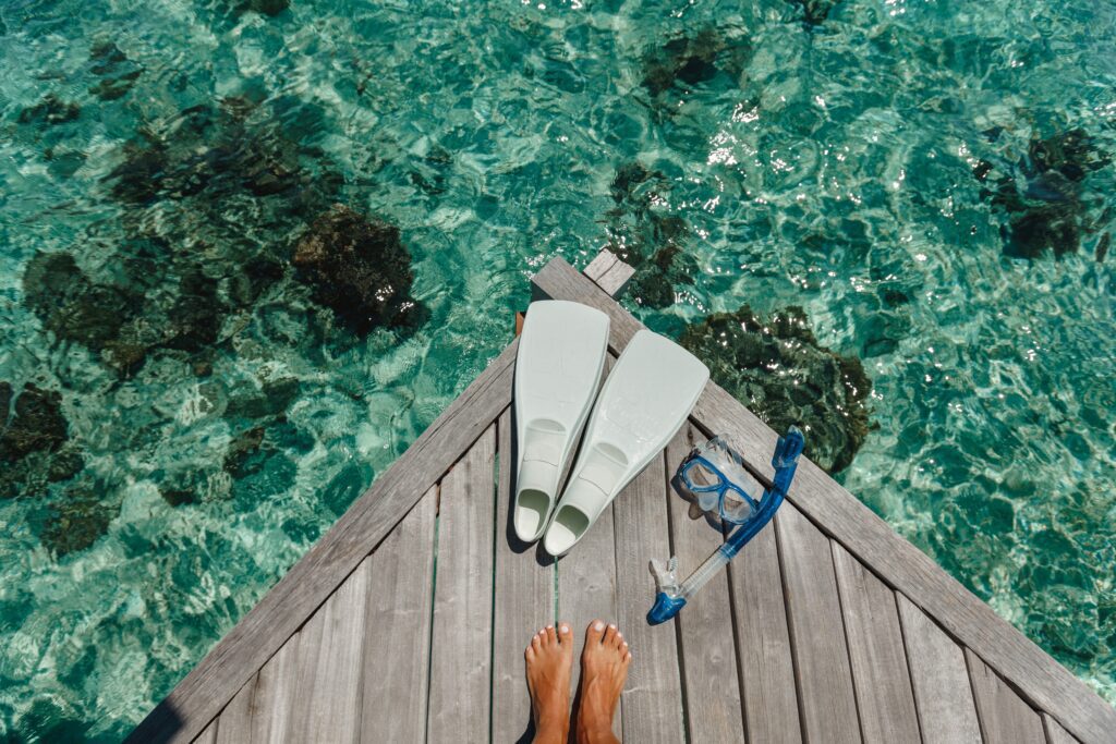 Woman Legs on Wooden Pier With Snorkeling Equipment.